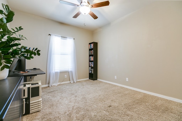 interior space featuring baseboards, a ceiling fan, and light colored carpet