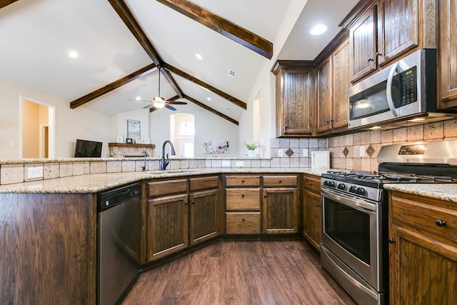 kitchen featuring tasteful backsplash, dark wood finished floors, lofted ceiling with beams, stainless steel appliances, and a sink