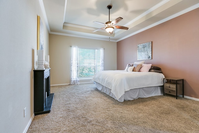 bedroom with carpet flooring, a ceiling fan, baseboards, a raised ceiling, and crown molding