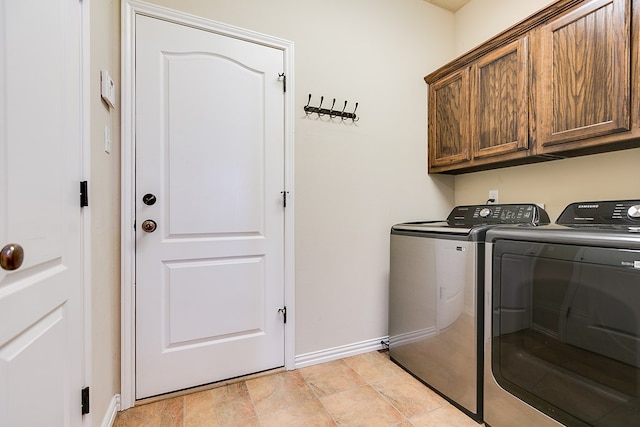 clothes washing area with washer and dryer, cabinet space, and baseboards