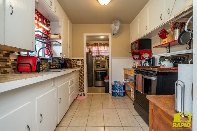113 N Belaire Ave, San Angelo, TX 76905 - kitchen featuring appliances with stainless steel finishes, white cabinets, light tile patterned flooring, light countertops, and tasteful backsplash
