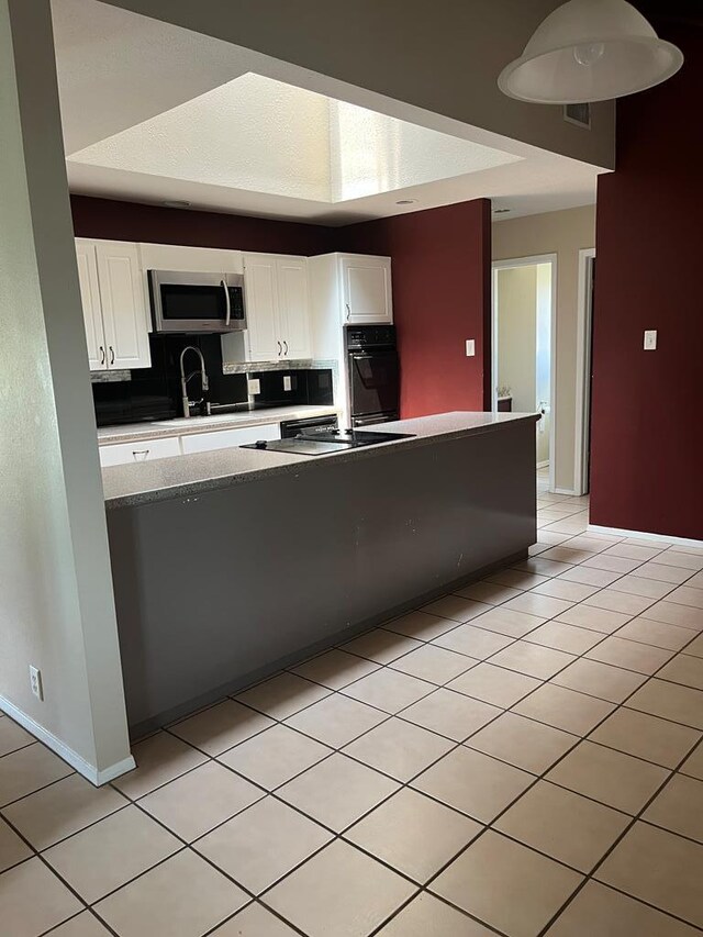 kitchen with light tile patterned flooring, white cabinets, and black appliances