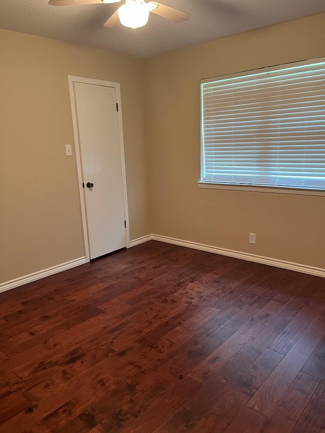 empty room featuring dark wood-type flooring and ceiling fan