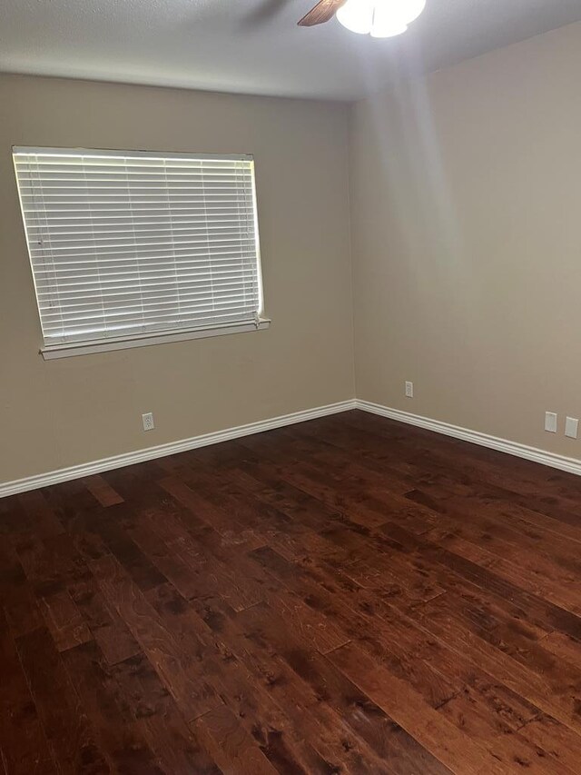 spare room featuring dark wood-type flooring and ceiling fan