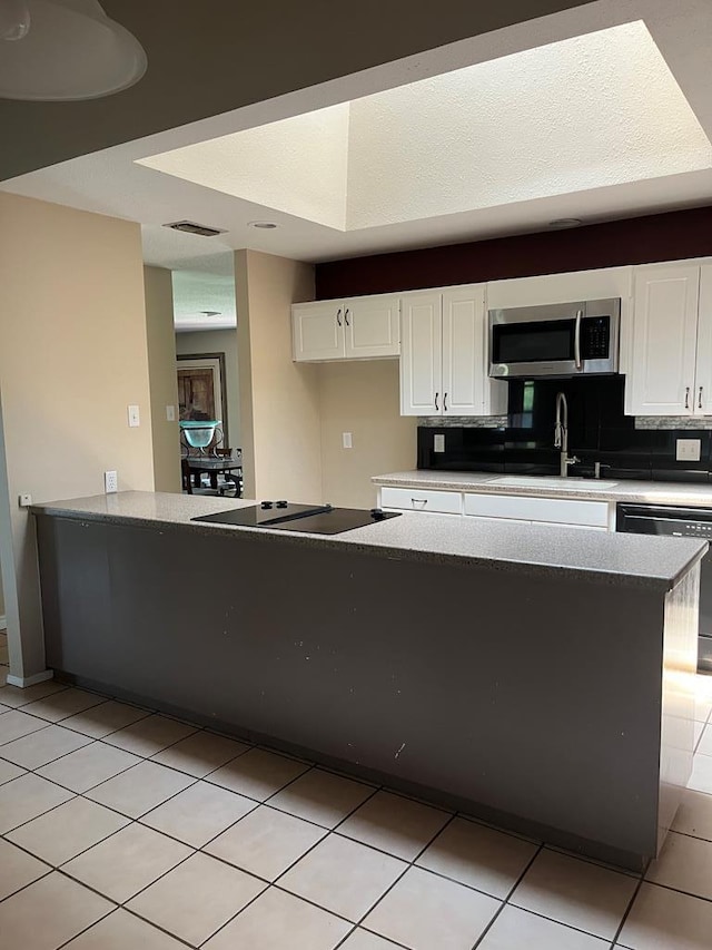 kitchen with light tile patterned floors, black appliances, sink, and white cabinets