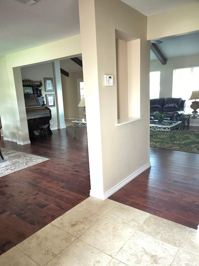 hall featuring beam ceiling, light hardwood / wood-style floors, and a textured ceiling