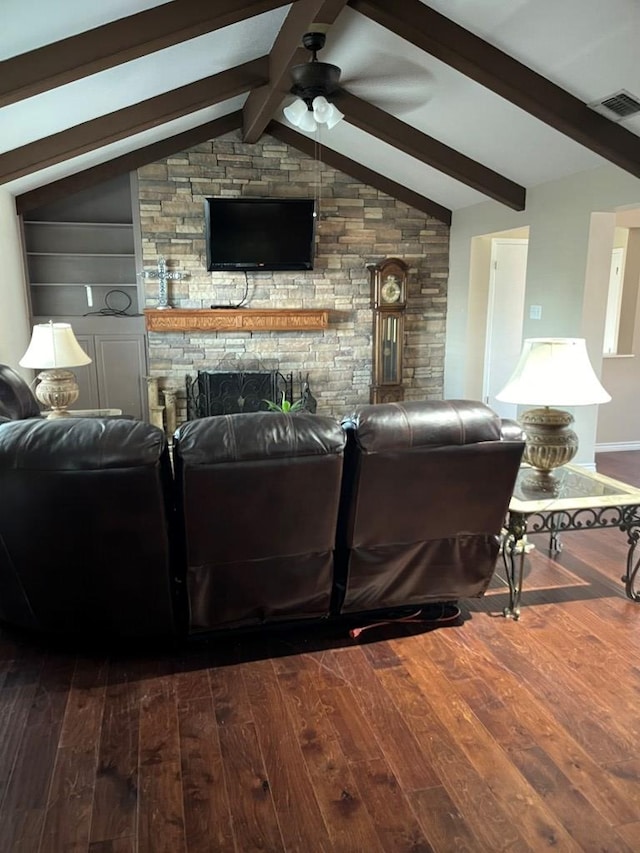 living room featuring dark wood-type flooring, built in shelves, a stone fireplace, vaulted ceiling, and ceiling fan