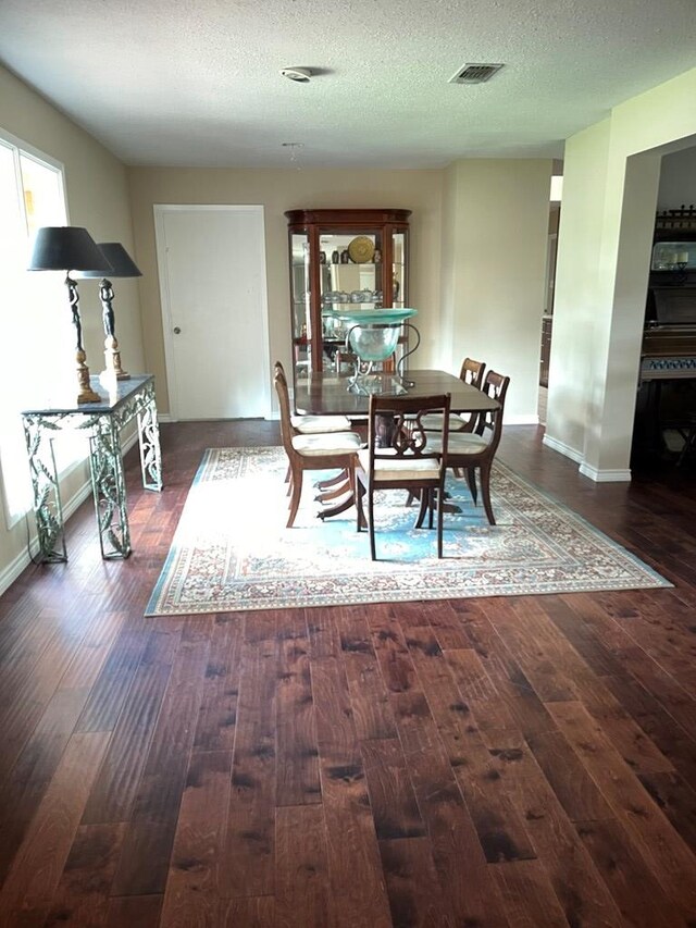 dining room featuring dark hardwood / wood-style floors and a textured ceiling