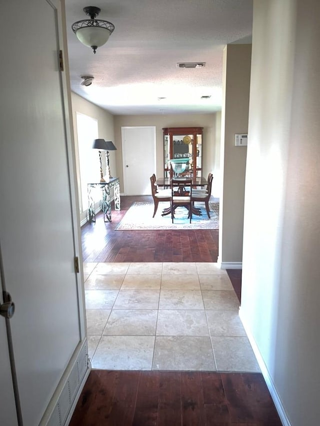 corridor with a healthy amount of sunlight, a textured ceiling, and light hardwood / wood-style flooring