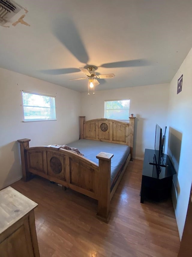 bedroom with multiple windows, dark wood-type flooring, and ceiling fan