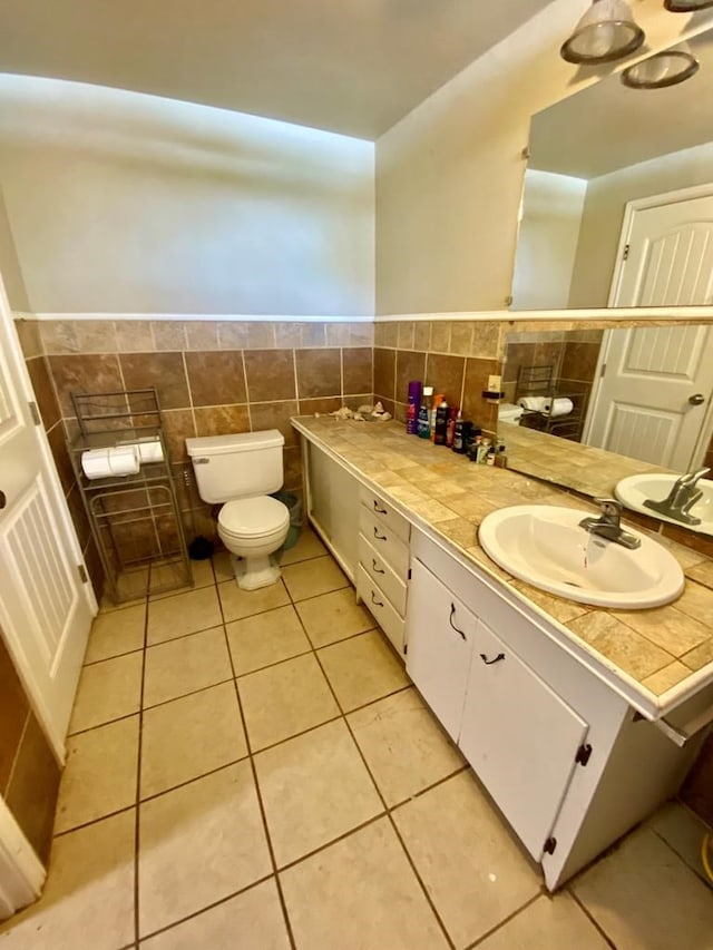 bathroom with vanity, toilet, tile patterned flooring, and tile walls