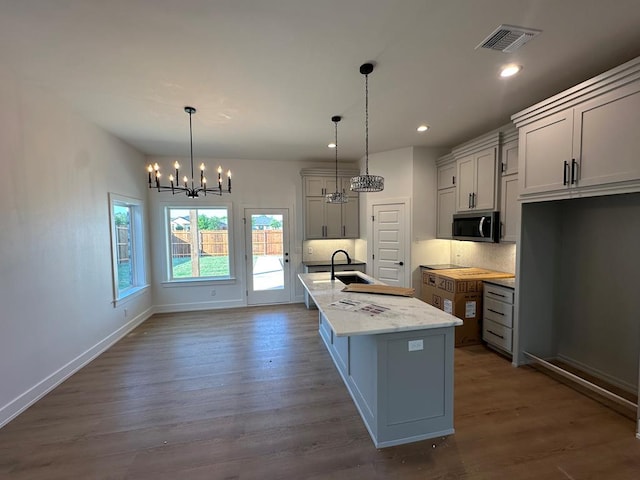 3615 Clearview Dr, San Angelo, TX 76904 - kitchen with stainless steel microwave, a chandelier, dark wood-style floors, a center island with sink, and a sink