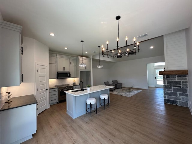 3615 Clearview Dr, San Angelo, TX 76904 - kitchen with appliances with stainless steel finishes, wood finished floors, open floor plan, a kitchen island with sink, and recessed lighting