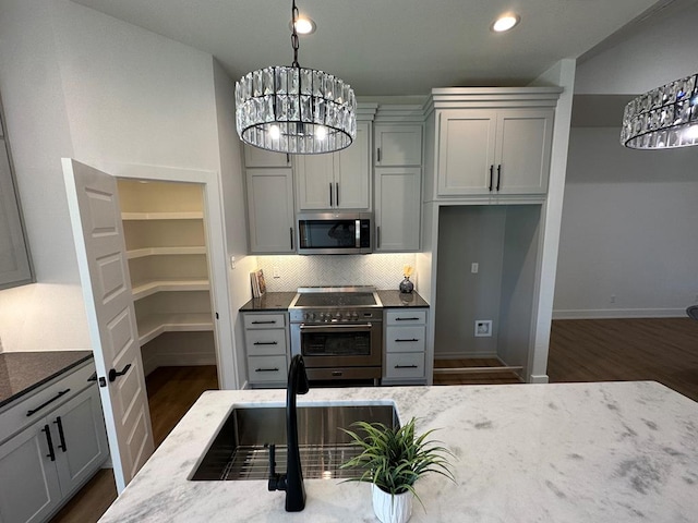 3615 Clearview Dr, San Angelo, TX 76904 - kitchen with appliances with stainless steel finishes, dark stone countertops, dark wood-type flooring, decorative backsplash, and recessed lighting