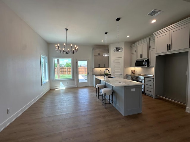 3615 Clearview Dr, San Angelo, TX 76904 - kitchen with appliances with stainless steel finishes, a chandelier, a kitchen breakfast bar, decorative backsplash, and dark wood-style floors