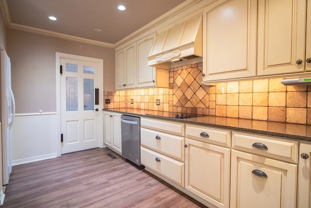 kitchen with crown molding, dark stone countertops, black electric cooktop, light hardwood / wood-style floors, and cream cabinetry