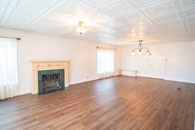 unfurnished living room featuring a notable chandelier, wood-type flooring, and a premium fireplace