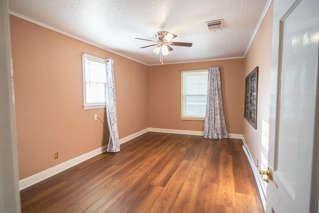 spare room with crown molding, plenty of natural light, and dark hardwood / wood-style floors