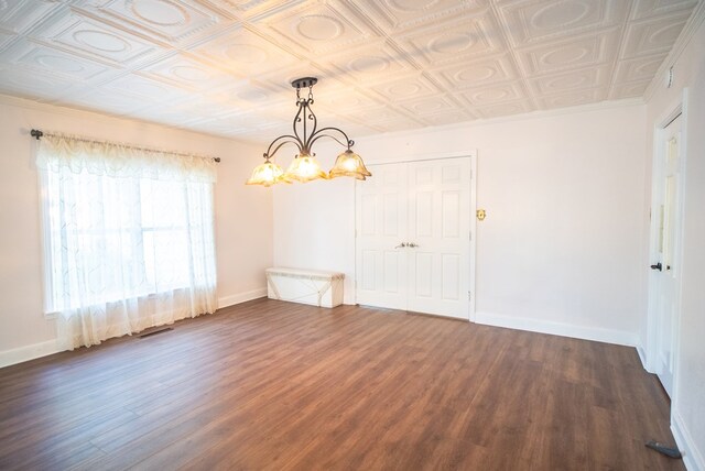 empty room with ornamental molding, dark hardwood / wood-style floors, and an inviting chandelier