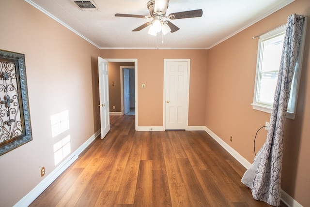 unfurnished bedroom featuring dark wood-type flooring, ornamental molding, and ceiling fan