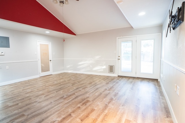 spare room featuring lofted ceiling, electric panel, and light wood-type flooring