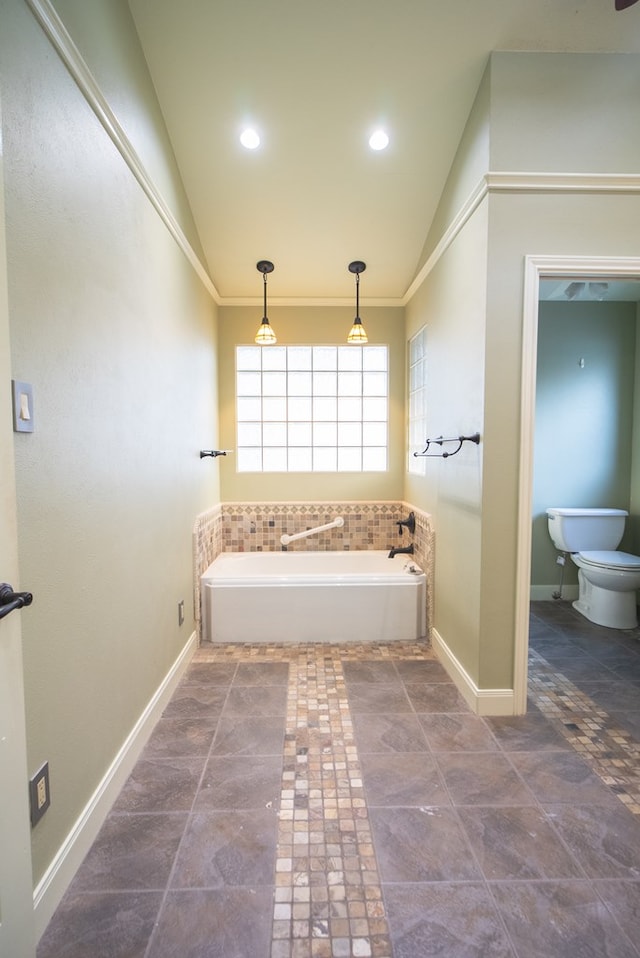 bathroom with vaulted ceiling, a tub to relax in, crown molding, and toilet