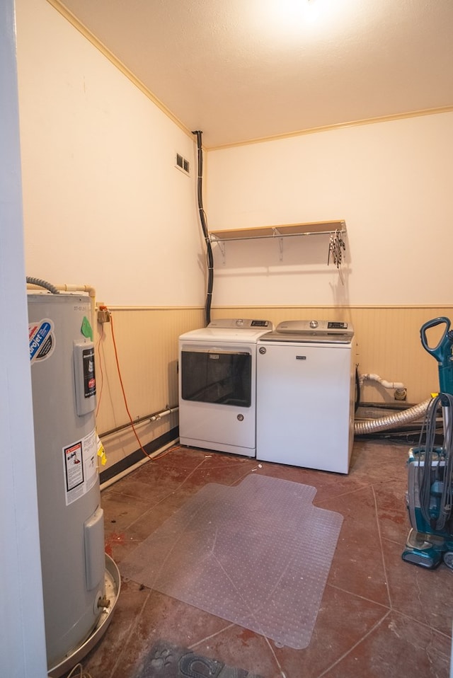 laundry area with ornamental molding, separate washer and dryer, electric water heater, and wood walls