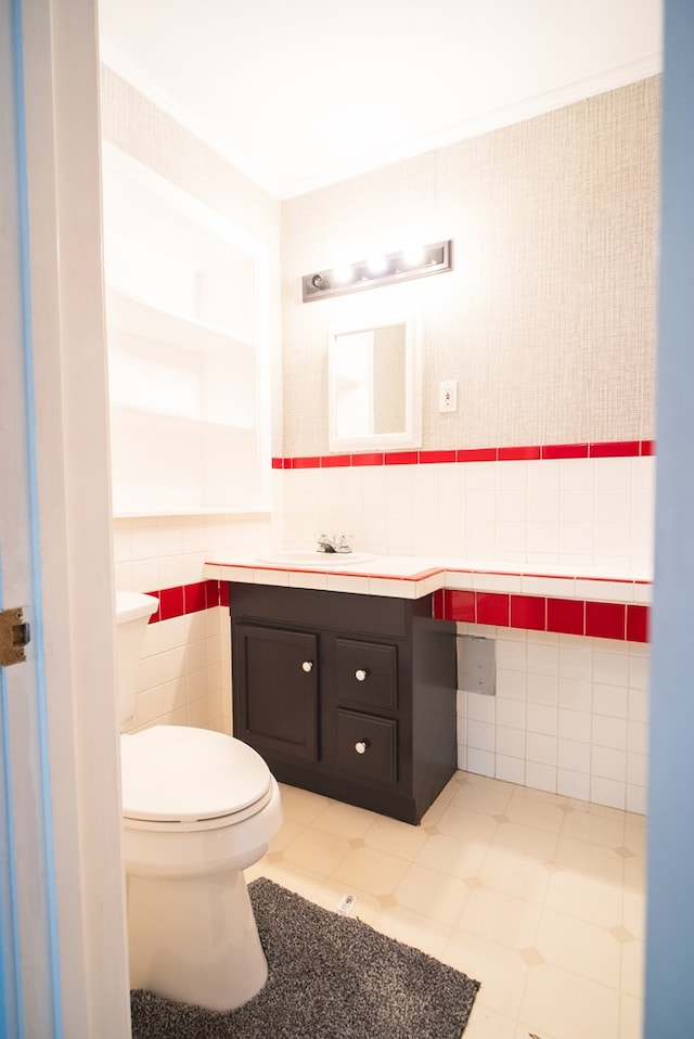 bathroom featuring vanity, tile walls, and toilet