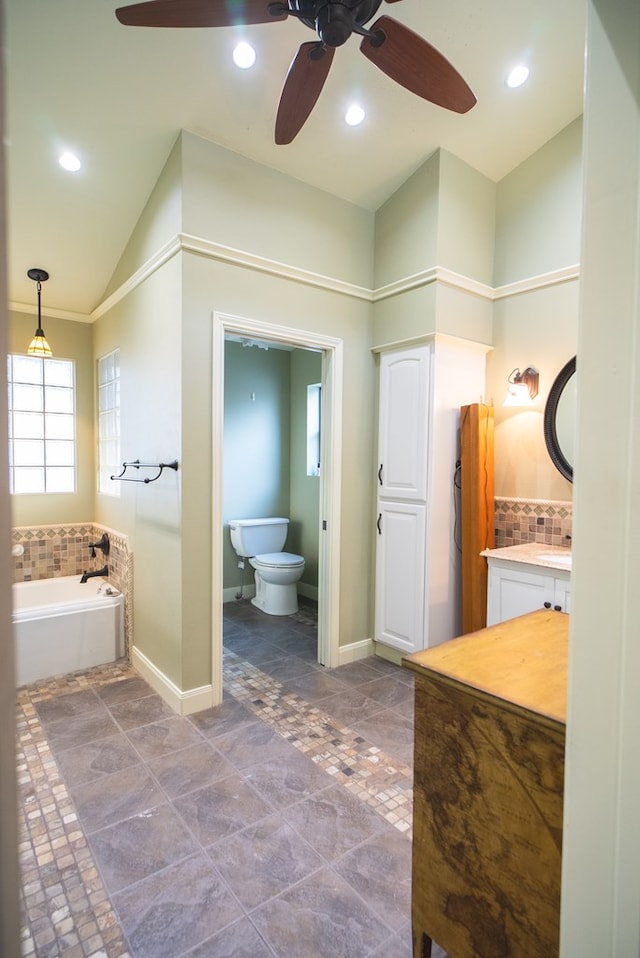 bathroom with lofted ceiling, toilet, vanity, decorative backsplash, and a washtub