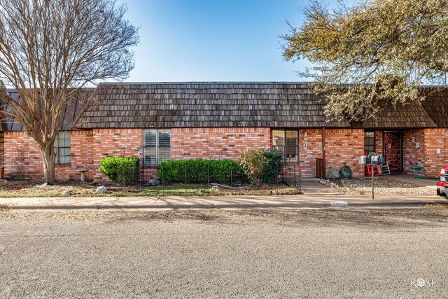 view of front of property with mansard roof and brick siding