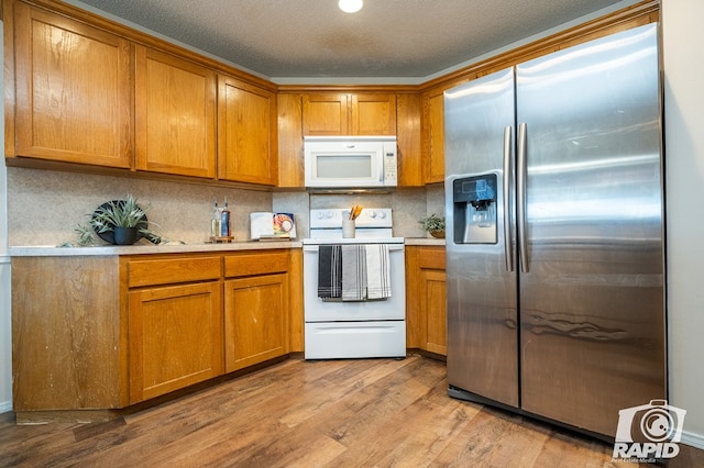 kitchen with white appliances, a textured ceiling, decorative backsplash, and light wood-type flooring