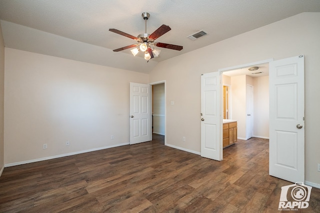 unfurnished bedroom featuring ensuite bathroom, vaulted ceiling, a textured ceiling, dark hardwood / wood-style floors, and ceiling fan