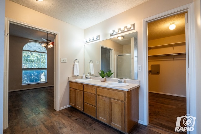 bathroom featuring a textured ceiling, vanity, a shower with door, hardwood / wood-style flooring, and ceiling fan