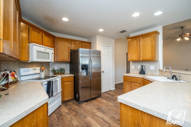 kitchen featuring sink, light hardwood / wood-style flooring, kitchen peninsula, white appliances, and backsplash