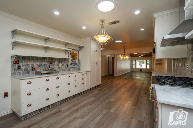 kitchen with hanging light fixtures, white cabinetry, tasteful backsplash, and wall chimney range hood