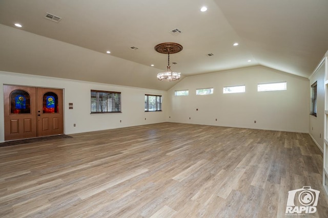 unfurnished living room with lofted ceiling, light hardwood / wood-style floors, and a chandelier