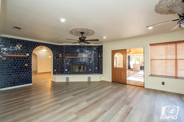 unfurnished living room featuring hardwood / wood-style flooring, crown molding, and ceiling fan