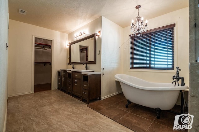 bathroom with tile patterned flooring, an inviting chandelier, vanity, a textured ceiling, and a tub to relax in