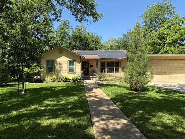 view of front of home featuring a garage, roof mounted solar panels, and a front yard