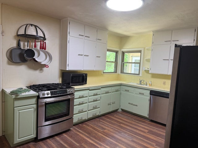 kitchen with light countertops, appliances with stainless steel finishes, a sink, and dark wood finished floors