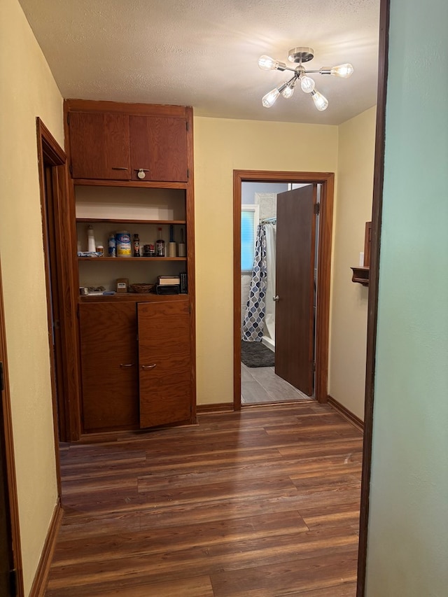 corridor featuring baseboards and dark wood-type flooring