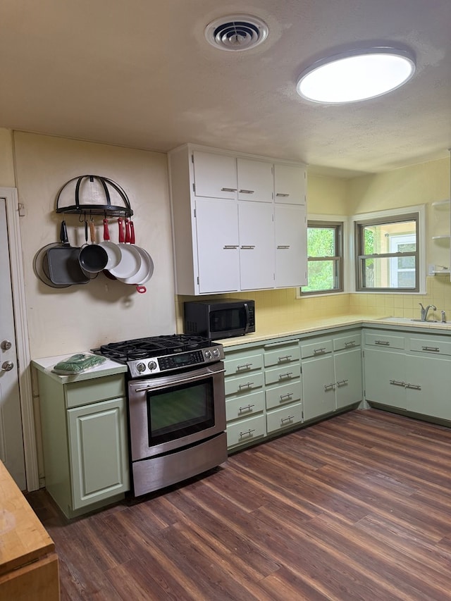 kitchen with black microwave, dark wood finished floors, gas stove, light countertops, and white cabinetry