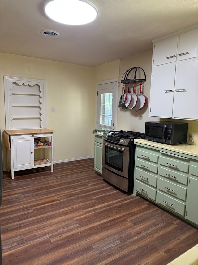 kitchen with black microwave, tile counters, dark wood-type flooring, green cabinetry, and stainless steel range with gas stovetop