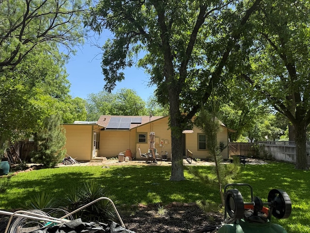 rear view of house featuring a lawn, a patio, a fenced backyard, and solar panels