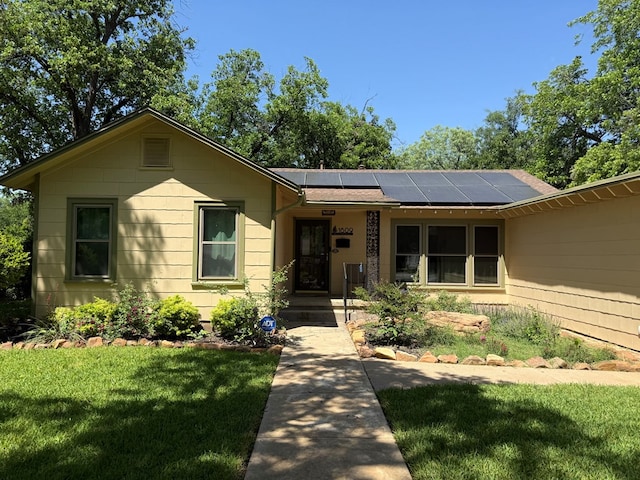 view of front of property with a front lawn, roof mounted solar panels, and roof with shingles