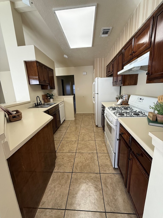 kitchen featuring visible vents, under cabinet range hood, a sink, white appliances, and light countertops