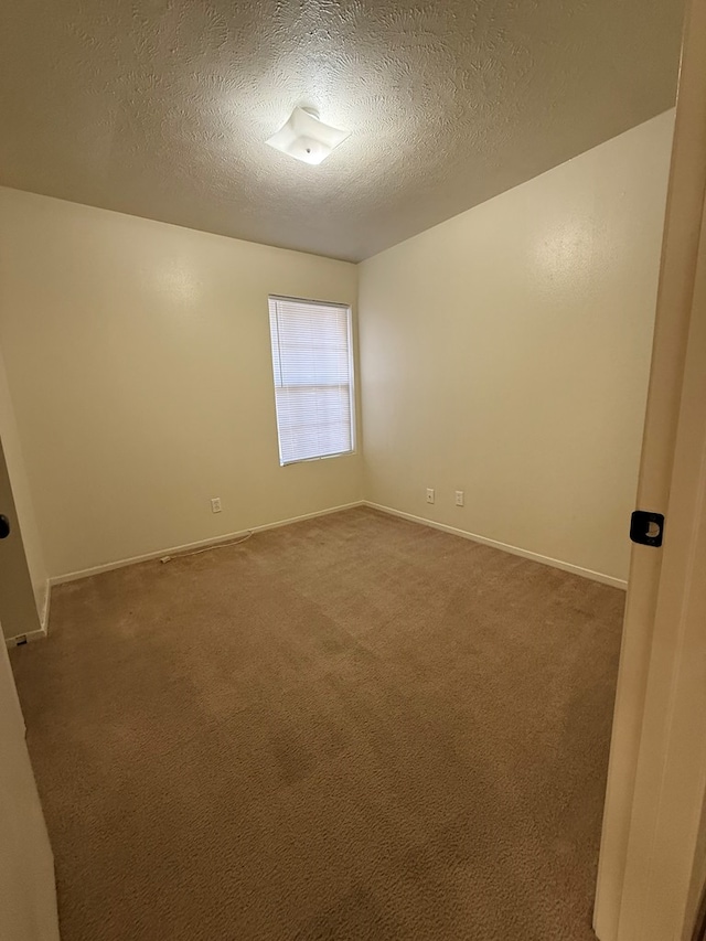 carpeted empty room featuring baseboards and a textured ceiling