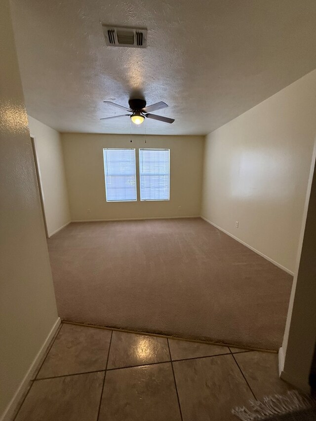 carpeted empty room with baseboards, a ceiling fan, visible vents, and a textured ceiling