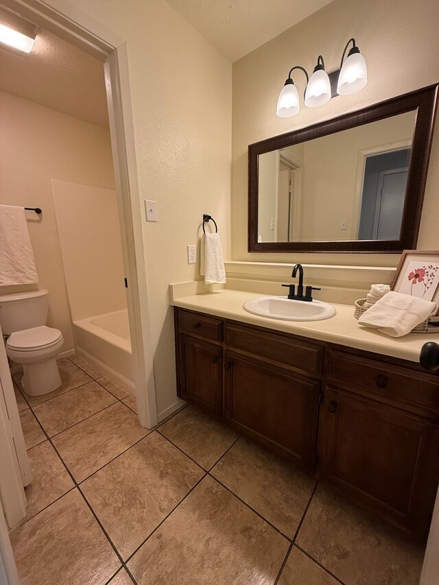 bathroom featuring a textured ceiling, toilet, vanity, and tile patterned flooring