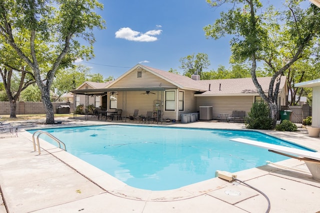 view of swimming pool with a patio area, ceiling fan, central air condition unit, and a diving board